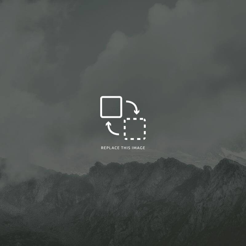 A peaceful outdoor setting with two cushioned wooden chairs on a gravel patio, framed by a white brick wall with yellow shutters, a central star-shaped decor, and hanging baskets of purple wisteria under a pergola.