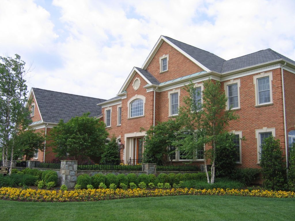 Landscape Plantings with Seasonal Flowers Stone Wall and Stone Piers Iron Railing