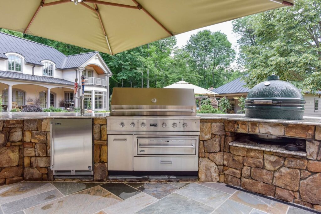 Outdoor Stone BBQ Island with Grill, Refrigerator, and Big Green Egg Granite Countertop Flagstone Patio