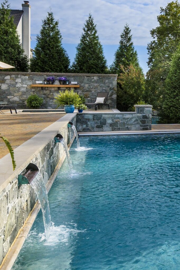 raised stone bond beam wall with waterfalls into pool