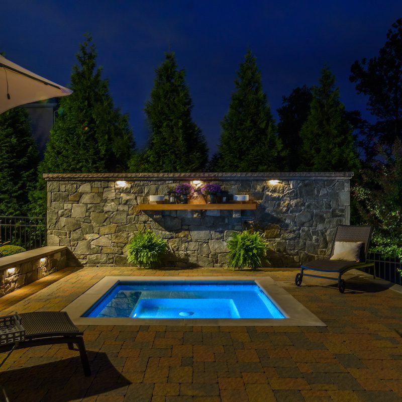 ingound spa and stone privacy wall with mantel