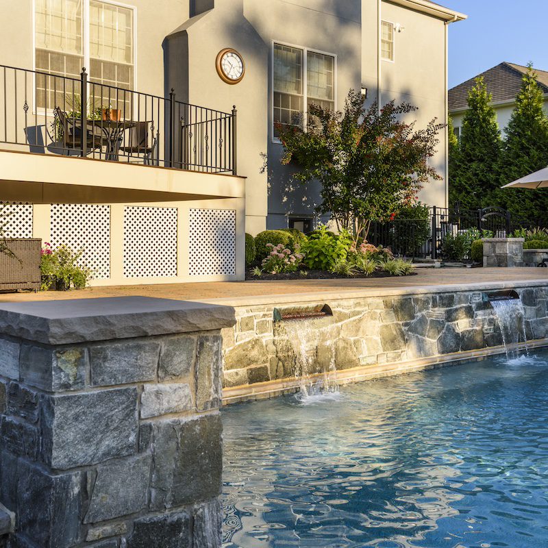 swimming pool with raised stone bond beam with waterfall into pool