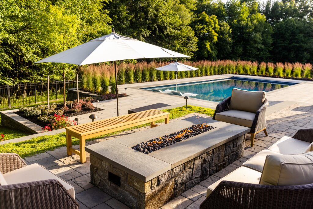 Clearwater Landscape & Nursery linear stone fire pit with lava rock media, paver patio and swimming pool