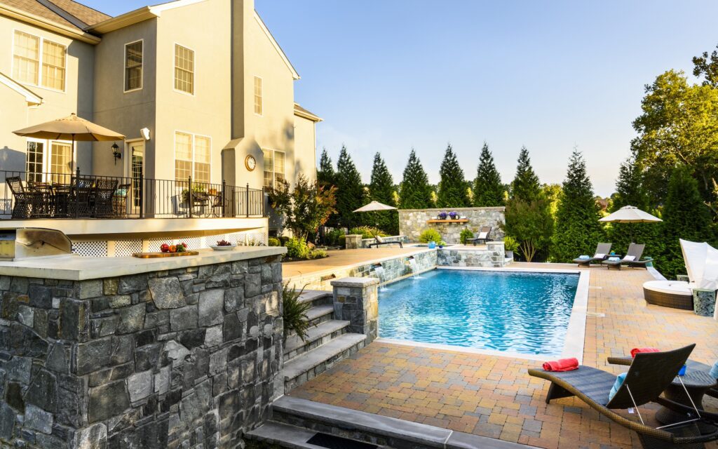 swimming pool with raised stone bond beam and paver pool deck