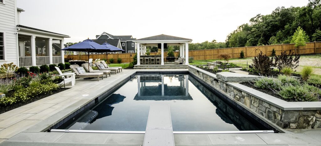 swimming pool with raised stone bond beam and paver pool deck