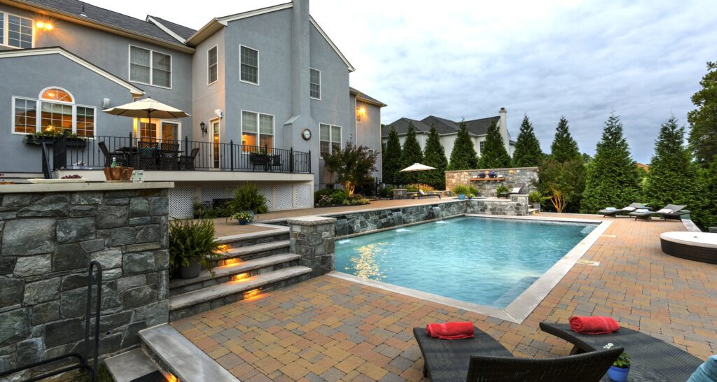 swimming pool with raised stone bond beam and paver pool deck