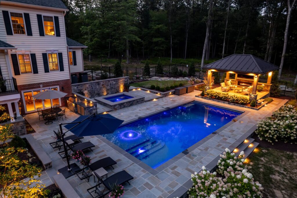 Backyard with custom swimming pool and spa Flagstone Patios Stone Retaining Walls Custom Pool Pavilion with Gas Fireplace Outdoor Kitchen