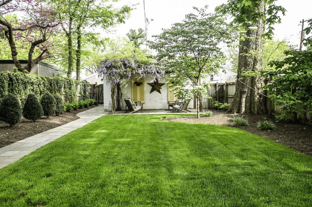 Decorative Gravel Patio Seating with Custom Pergola with Wisteria Lush Turf Area Lawn Landscape Plantings Flagstone Walkway