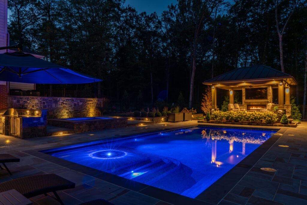 Backyard with custom swimming pool and spa Flagstone Patios Stone Retaining Walls Custom Pool Pavilion with Gas Fireplace Outdoor Kitchen