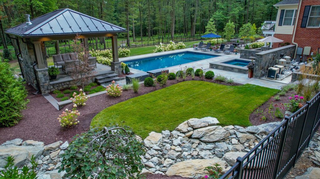 Swimming pool and spa in backyard with hardscape stone dry creek bed turf and landscape plantings