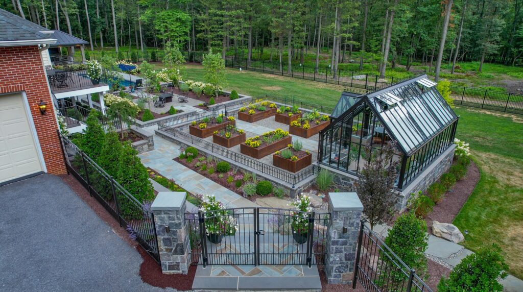 Hartley Botanic Glass Greenhouse on a stone foundation Corten Steel Planters Flagstone Walkways Stone Entry Piers with Gate