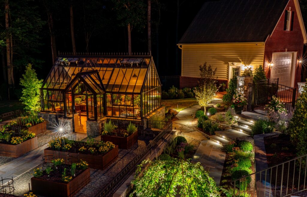 Backyard garden project with Hartley Botanic Glass Greenhouse and raised Corten steel garden planters. Landscape Plantings Low Voltage Lighting Flagstone Walkway with Stone Steps Stone Entry Piers with Wrought Iron Gates