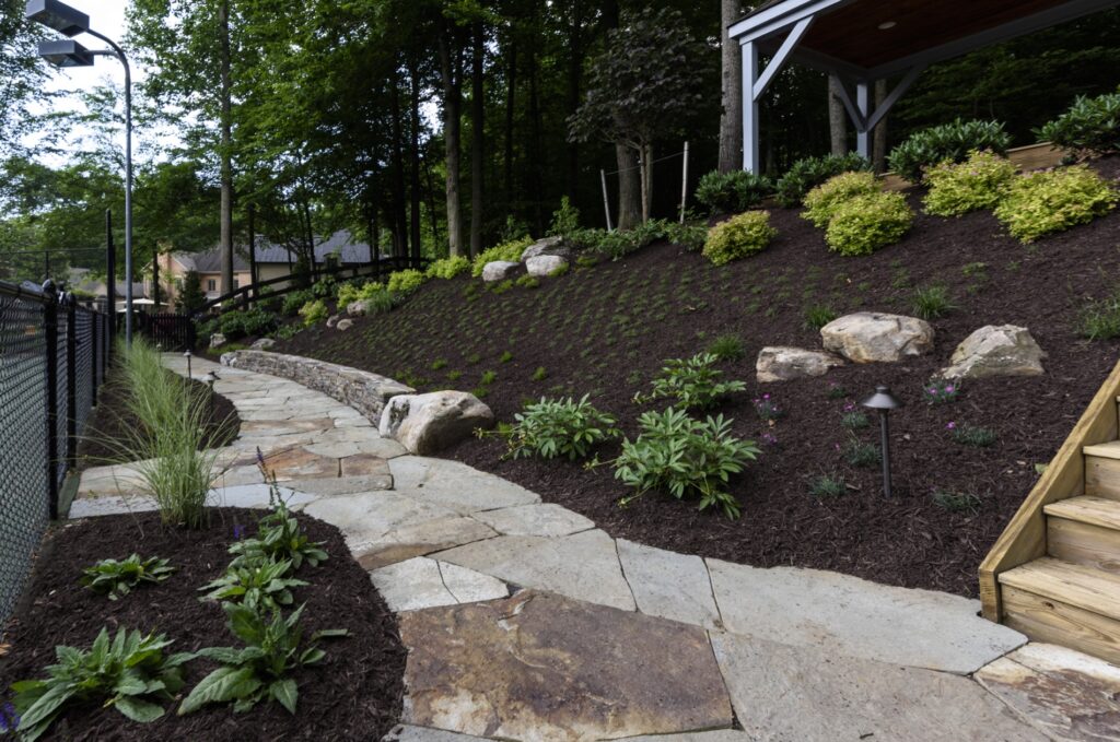 flagstone walkway with stone garden wall and hillside landscape plantings