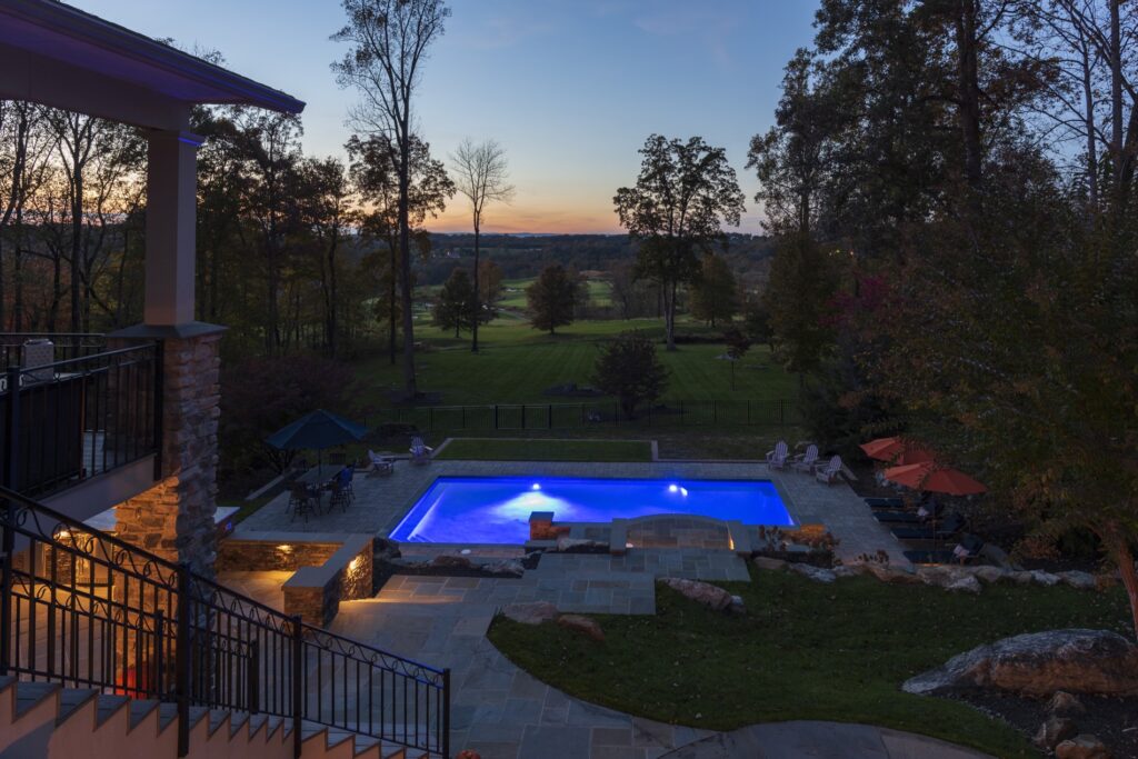 Swimming pool in backyard with paver pool deck flagstone walkway and stone steps low voltage lighting