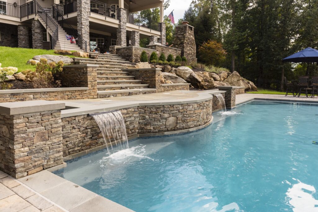 stone retaining walls with steps and waterfall scuppers into swimming pool