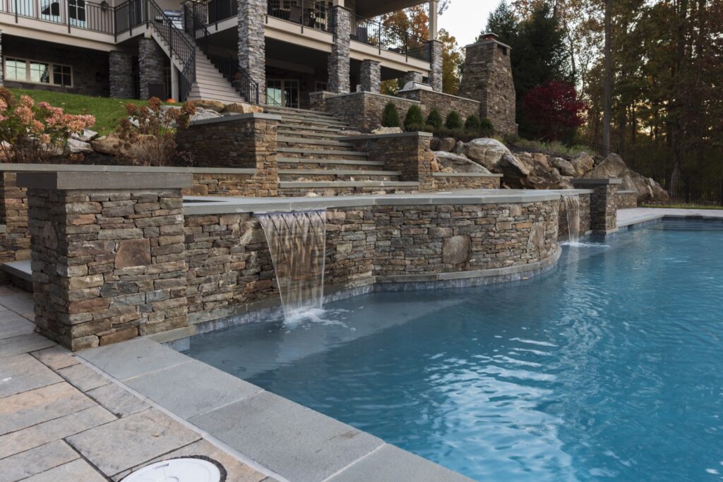 Stone retaining walls with steps custom swimming pool with water spill scuppers