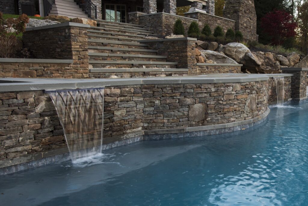 Stone retaining walls with steps custom swimming pool with water spill scuppers