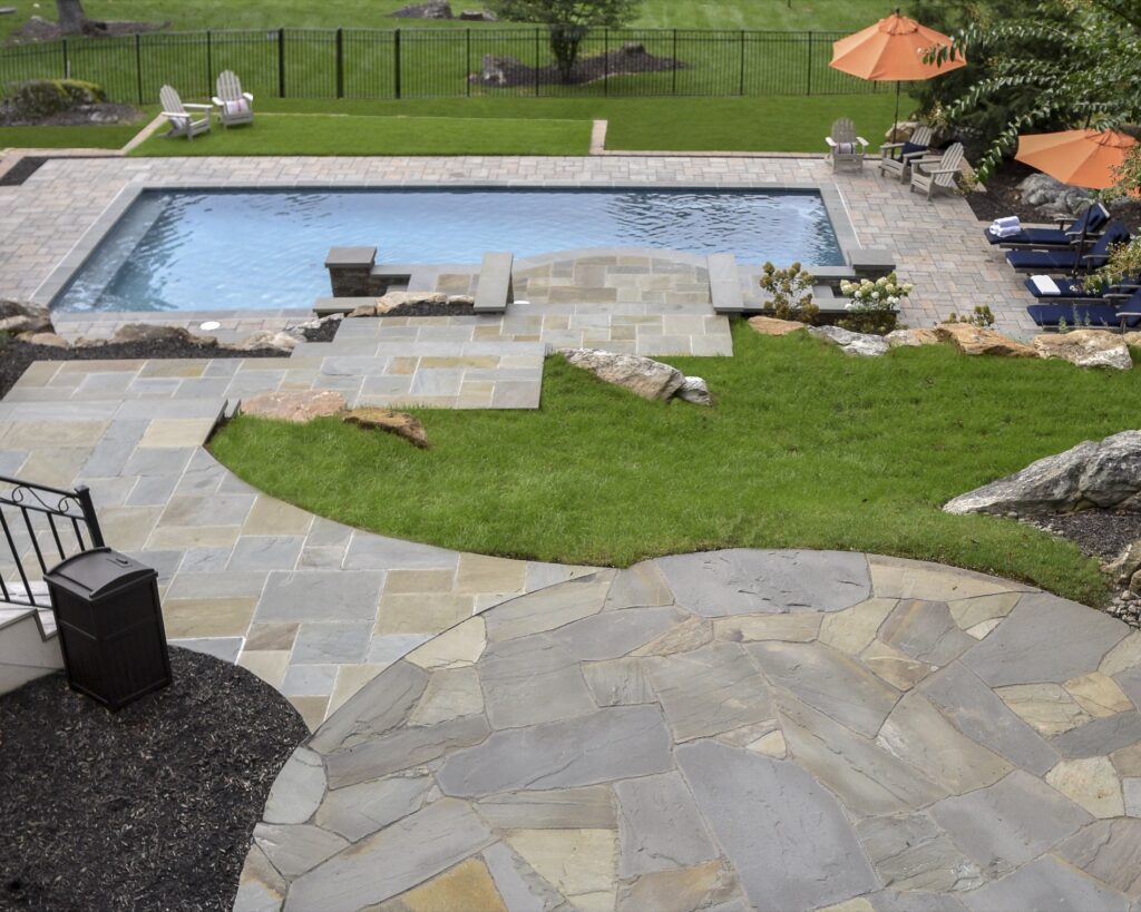 Swimming pool in backyard with paver pool deck flagstone walkway and stone steps