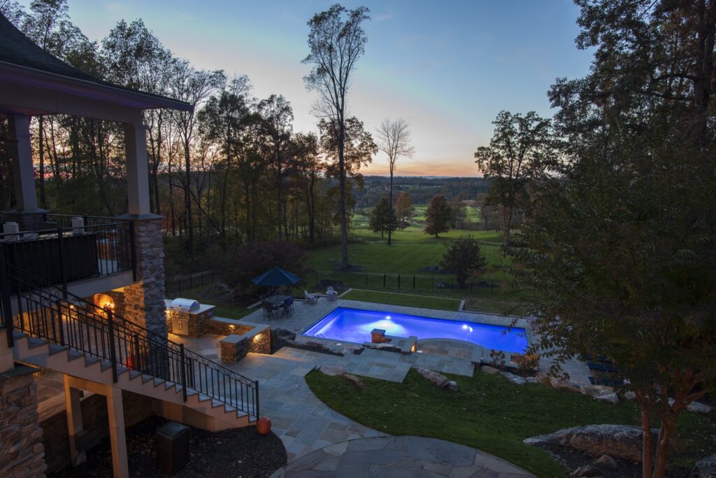 Swimming pool in backyard with paver pool deck flagstone walkway and stone steps low voltage lighting