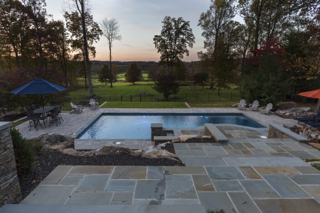 Swimming pool in backyard with paver pool deck flagstone walkway and stone steps